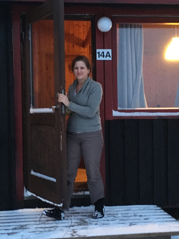 Personne debout dans l'embrasure de la porte d'une cabane en bois en hiver