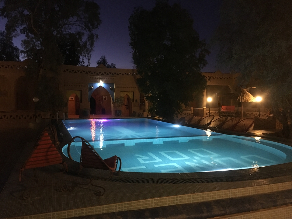 Piscine d'un complexe hôtelier avec éclairage de soirée.