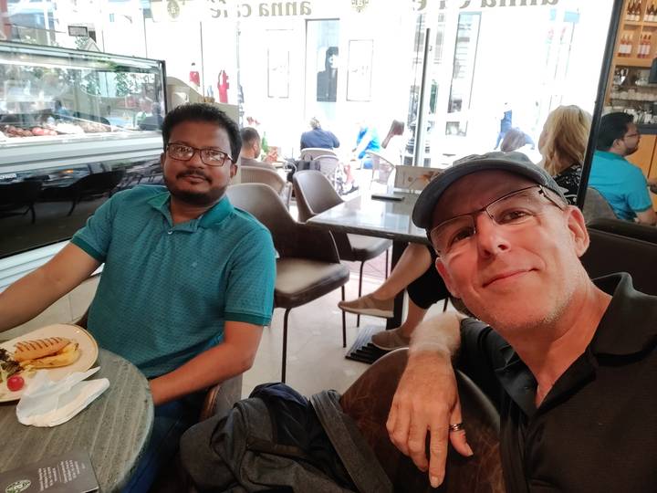 Des gens assis dans un café, l'un d'eux mangeant un sandwich.