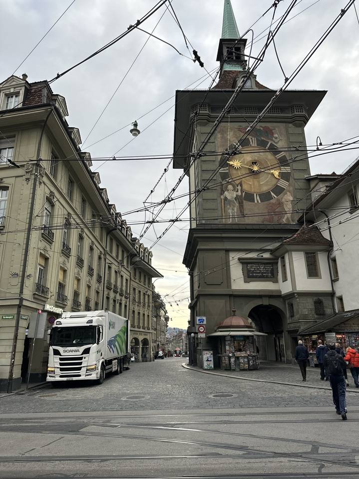 Scène de rue avec un clocher et un camion.