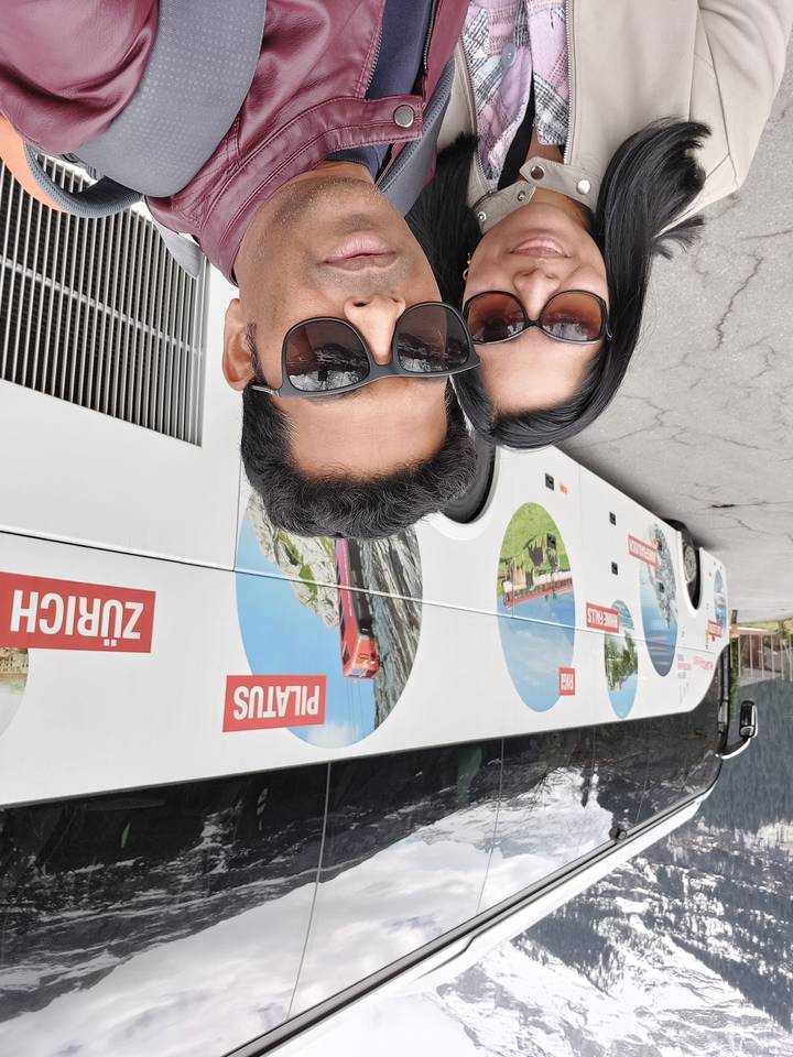 Un couple posant devant un bus avec « Pilatus » et « Zurich » en arrière-plan.