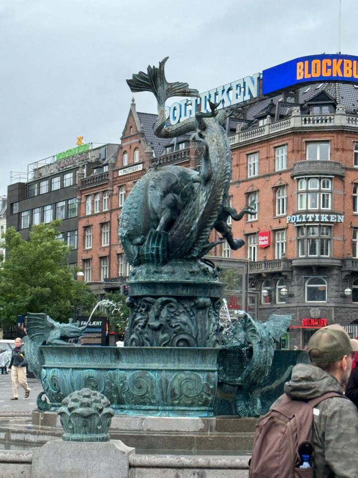 Sculpture d'une créature mythique avec un paysage urbain en arrière-plan.