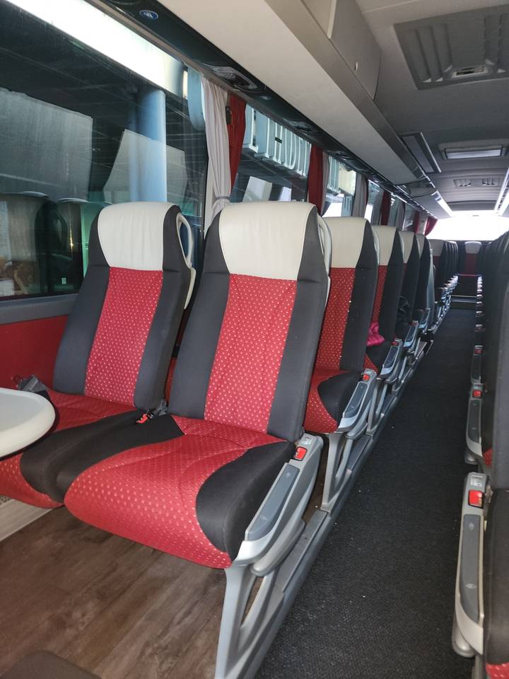 Intérieur d'autobus avec des rangées de sièges rouges et noirs.