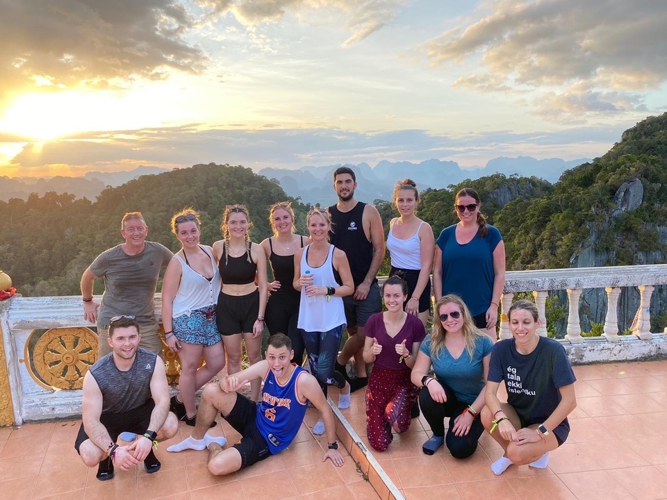 Groupe de personnes au sommet d'une montagne avec une vue sur le coucher de soleil.