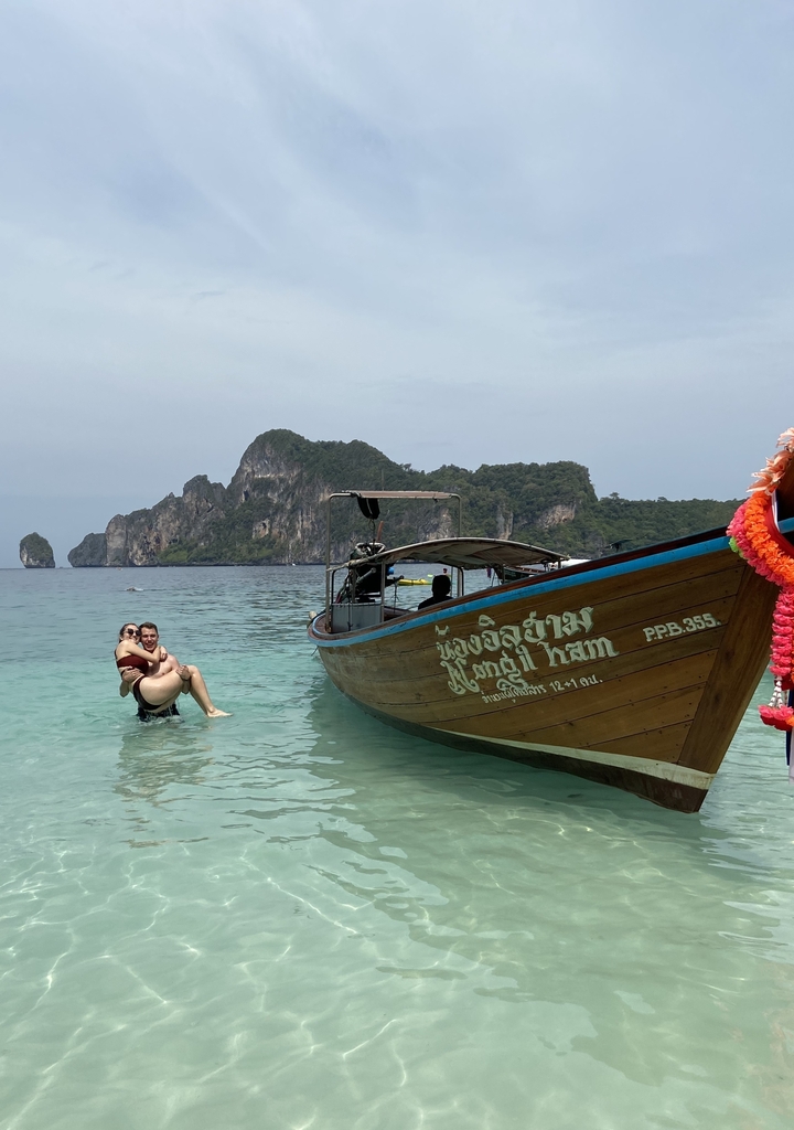 Couple profitant d'une journée à la plage avec un bateau traditionnel.