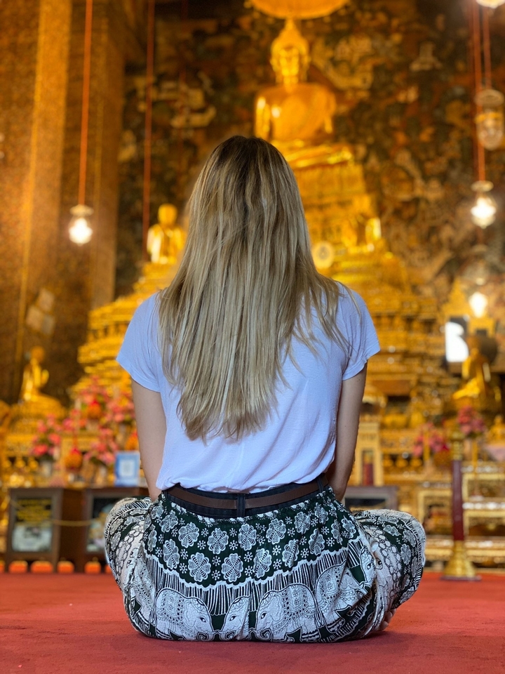 Personne face à une statue de Bouddha dorée dans un temple.