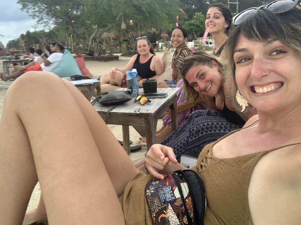 Groupe de personnes souriantes prenant la pose pour un selfie dans un café en bord de mer.