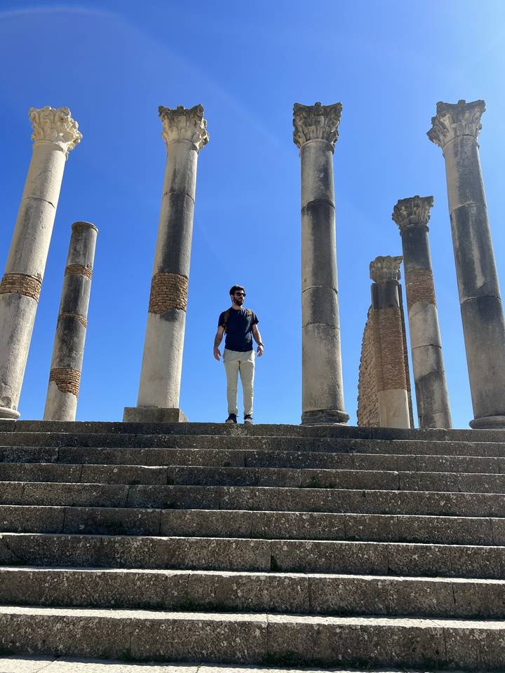 Personne debout parmi des ruines antiques avec des colonnes.