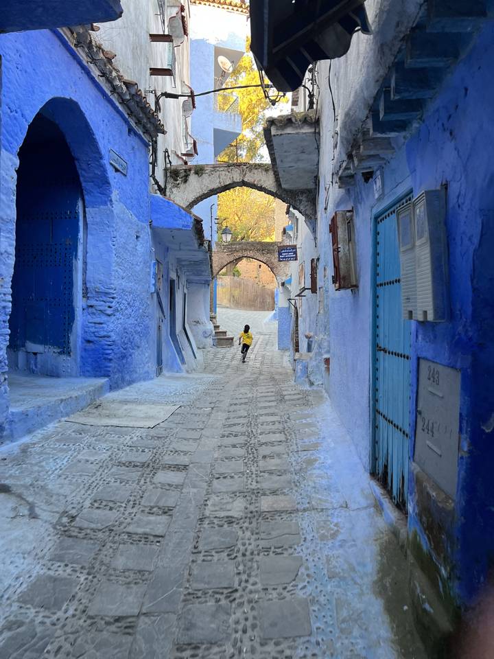 Rue étroite avec des murs peints en bleu et des arcades.