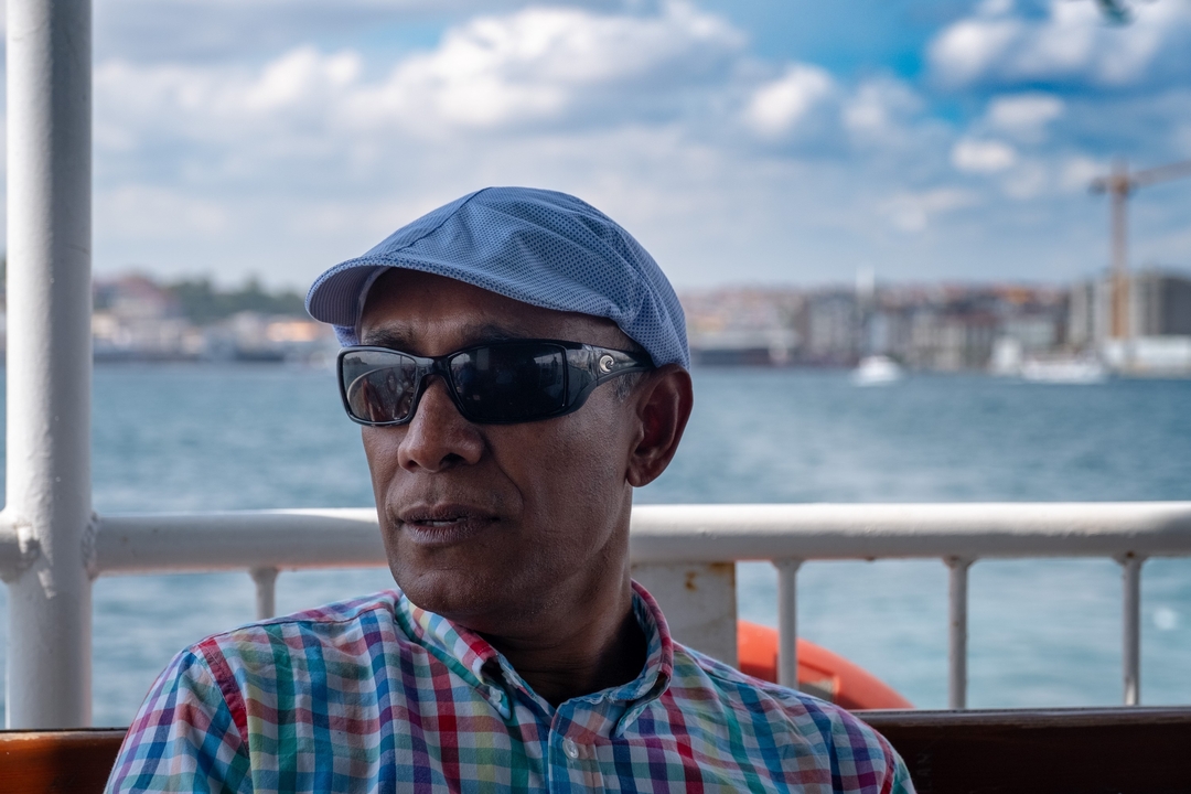 Homme sur un bateau avec un paysage urbain en arrière-plan.