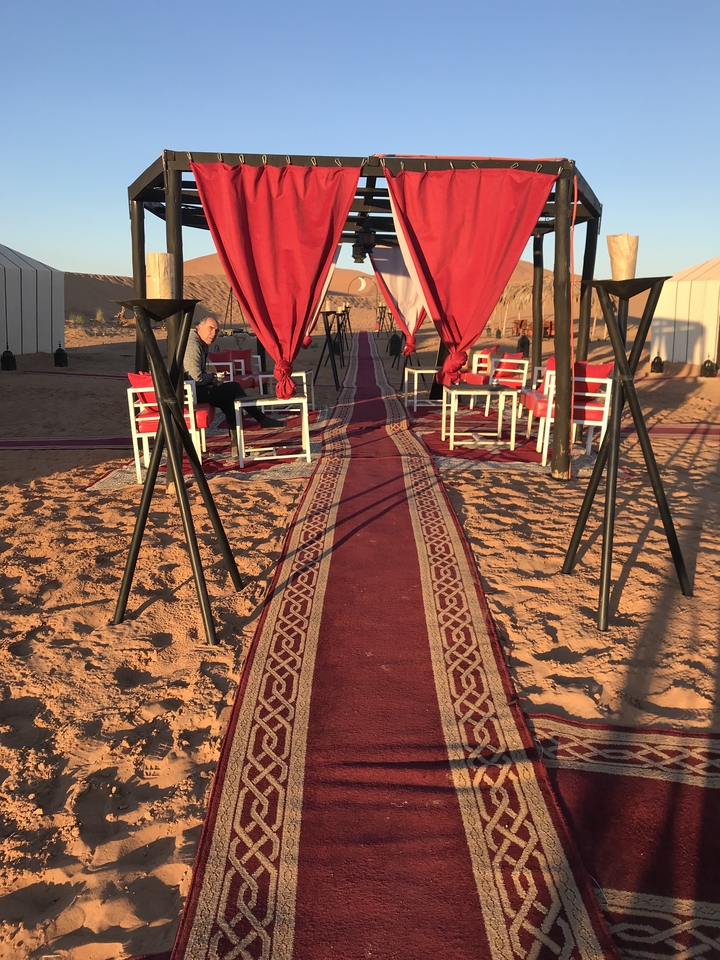 Aménagement de sièges extérieurs avec tapis rouge dans un décor désertique.