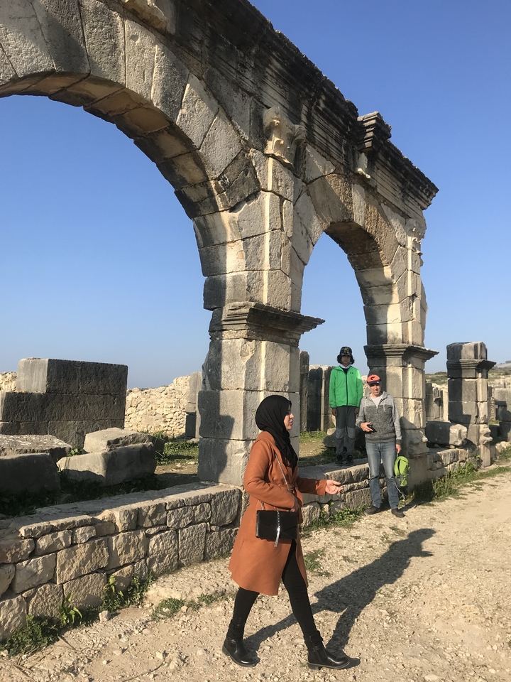 People exploring ancient ruins with an archway.