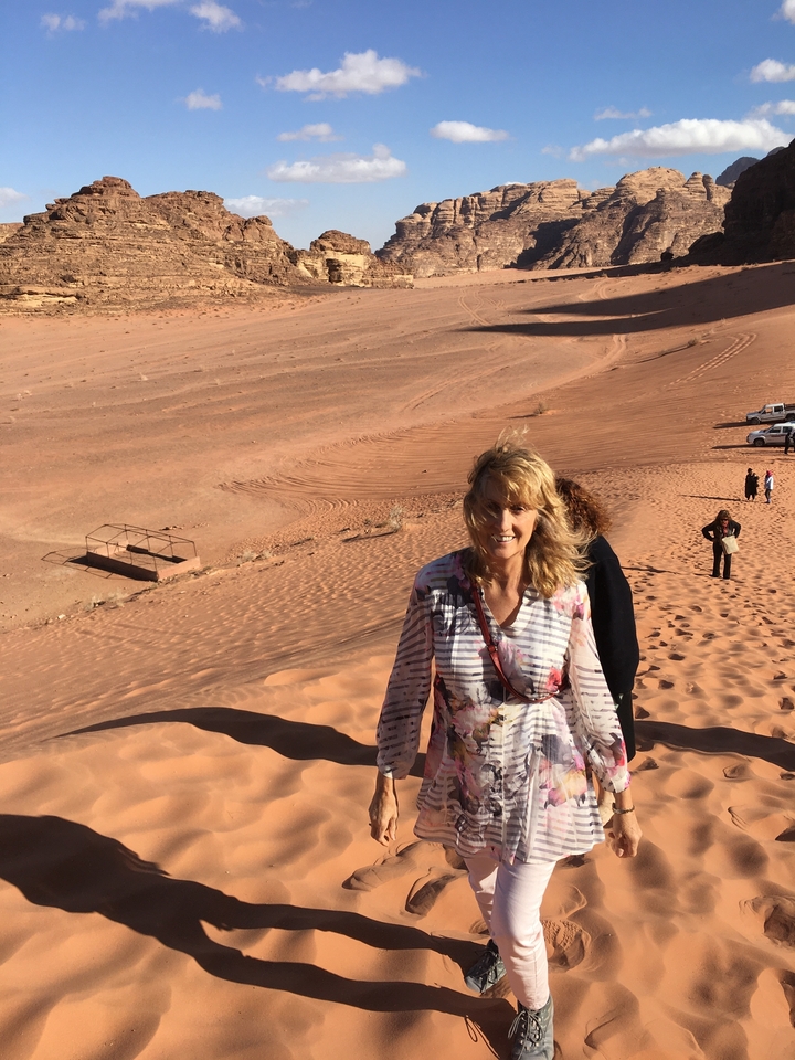 Personne escaladant des dunes de sable avec d'autres en arrière-plan au Wadi Rum.