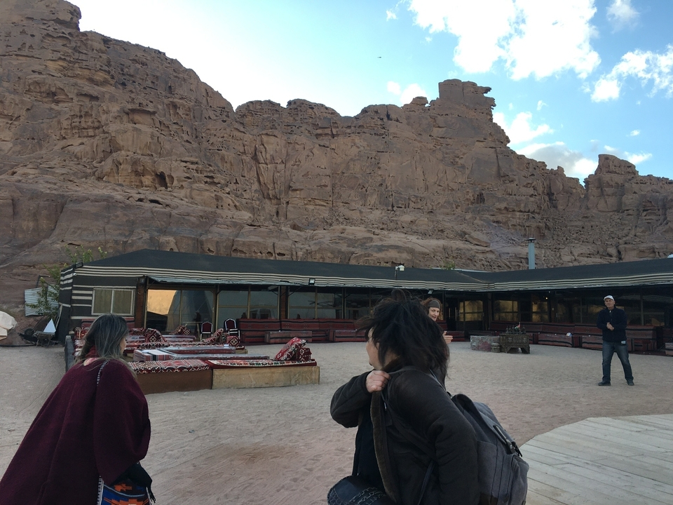 Des gens à l'extérieur de bâtiments traditionnels avec un arrière-plan montagneux.