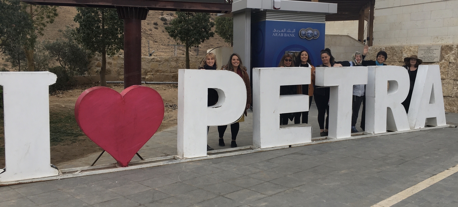 Groupe de personnes posant avec un panneau « J'aime Pétra ».