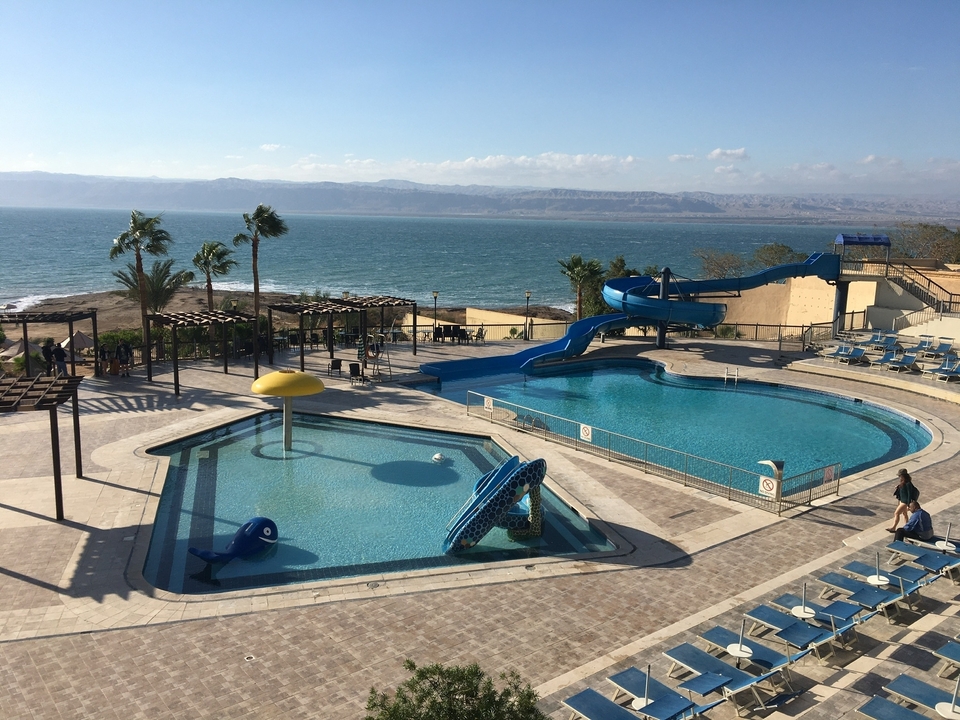 Zone de piscine avec vue sur une grande étendue d'eau et des montagnes.