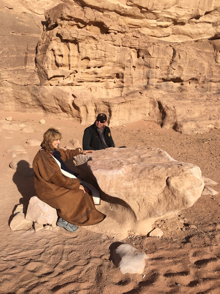 Deux personnes assises sur des rochers dans un décor désertique.
