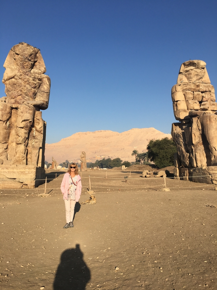 Femme debout avec des structures de pierre anciennes et un paysage désertique.