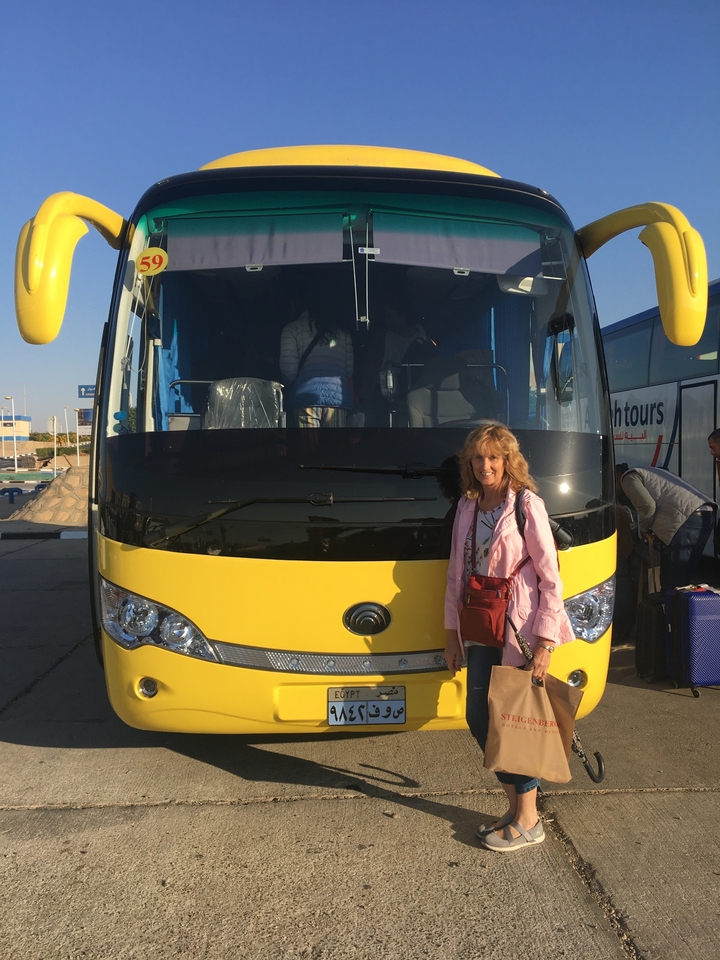 Femme debout près d'un autocar de tourisme dans une zone de stationnement.