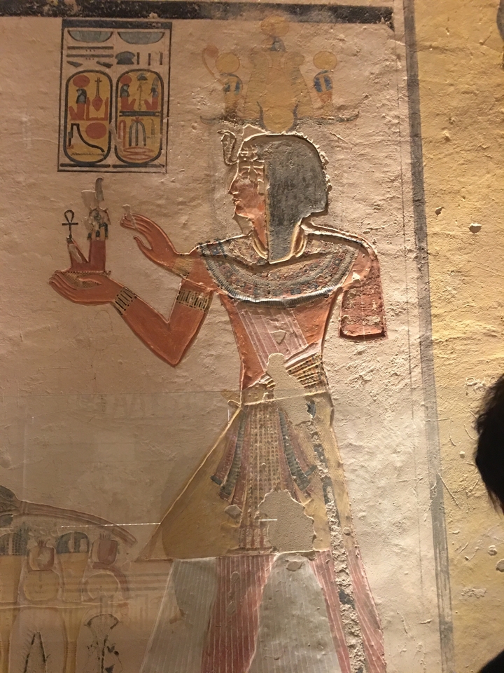Peinture murale égyptienne antique avec un personnage tenant une ankh.