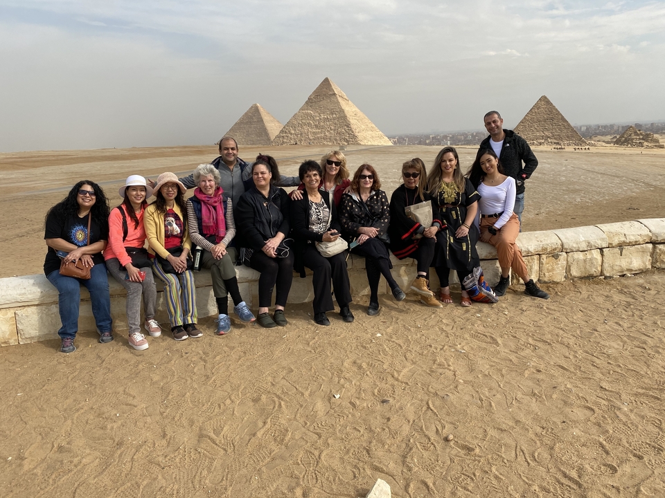 Groupe de personnes assises devant les pyramides.