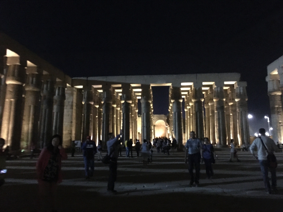 Vue nocturne du temple de Louxor avec des personnes et des éclairages.