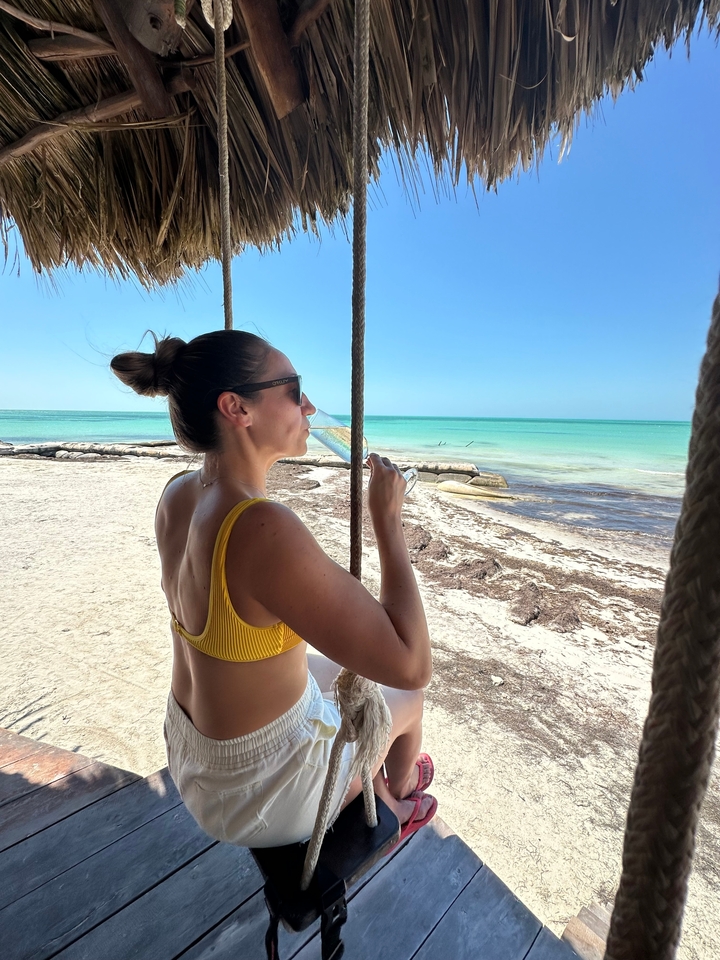 Femme savourant une boisson dans un lieu en bord de mer.