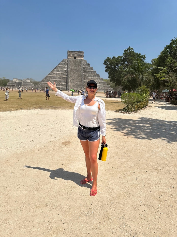 Femme pointant du doigt une pyramide au loin.