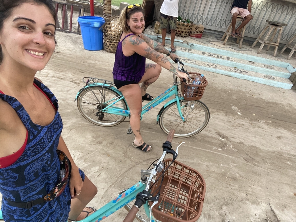 Deux femmes à vélo près d'un sentier dans une zone côtière.