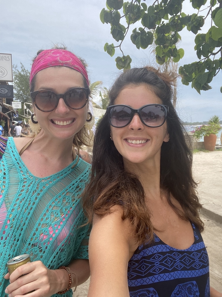 Deux femmes prennent un selfie sur une plage sous un ciel nuageux.