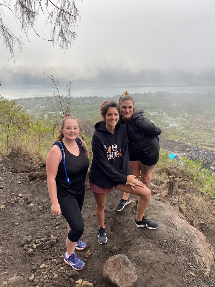 Trois femmes debout sur le flanc d'une montagne avec vue sur une vallée.