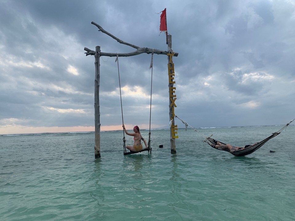 Une personne sur une balançoire et une autre dans un hamac dans la mer.