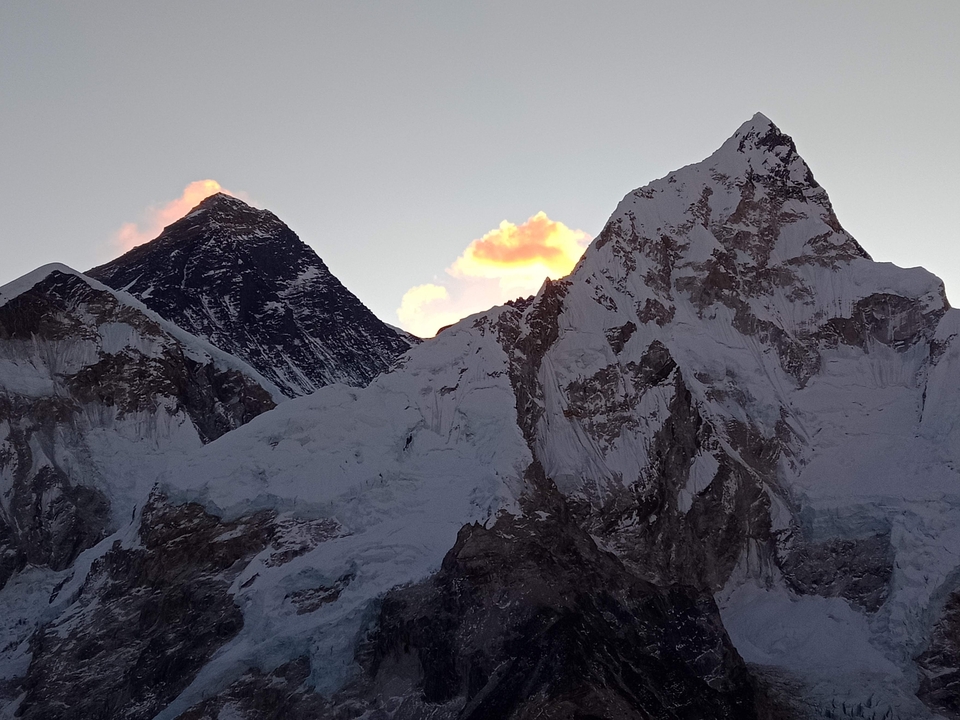 Montagnes avec de la neige et des nuages lumineux pendant le coucher du soleil.