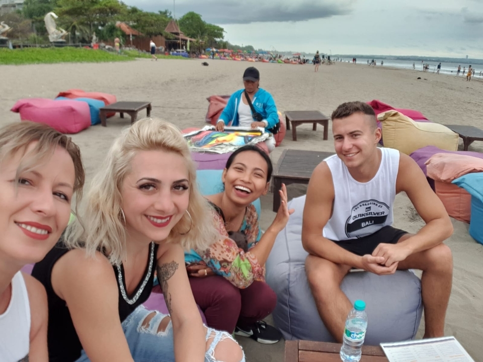 Groupe de personnes assises sur une plage de sable.