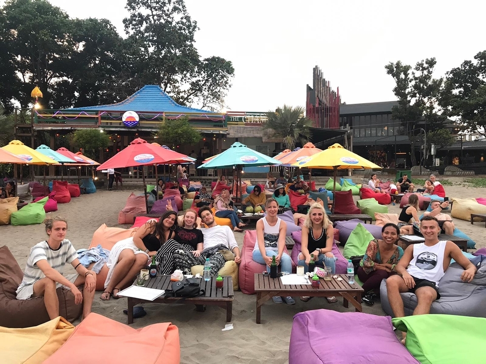 Des gens se prélassant sur une plage de sable avec des parasols colorés.