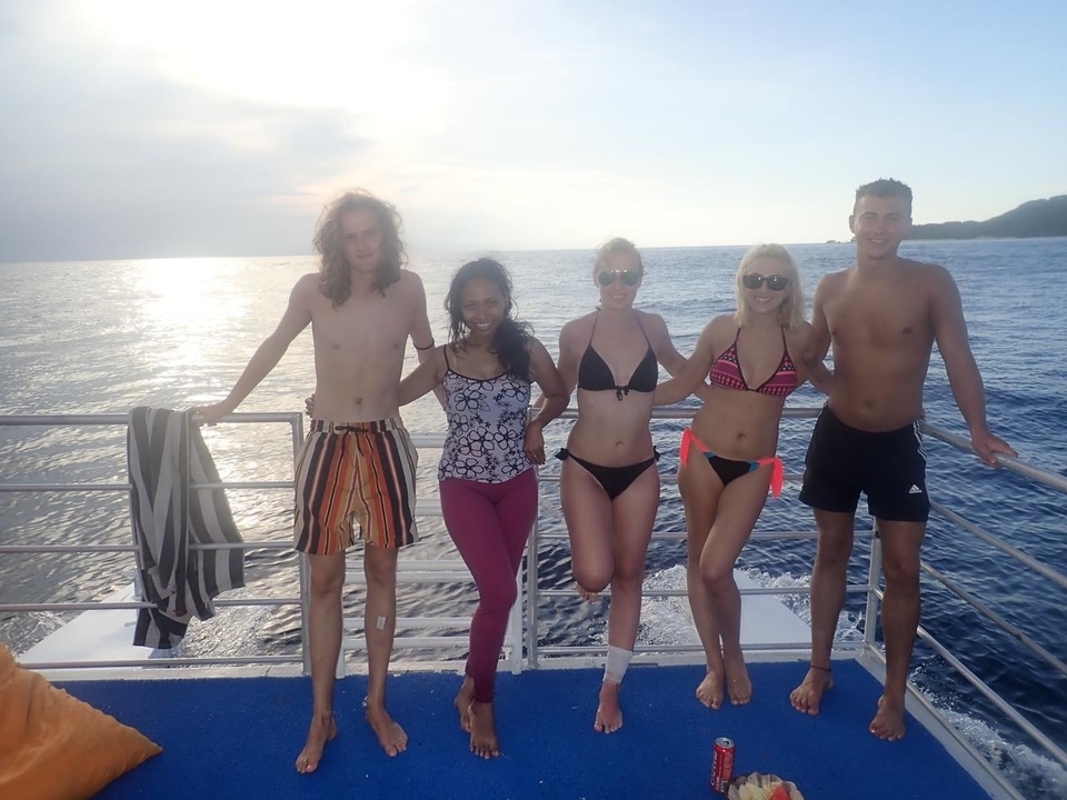 Groupe de personnes sur un bateau en mer au coucher du soleil.