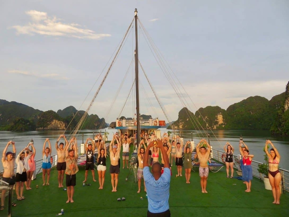 Un groupe de personnes faisant des exercices sur un bateau avec des falaises calcaires pittoresques tout autour.