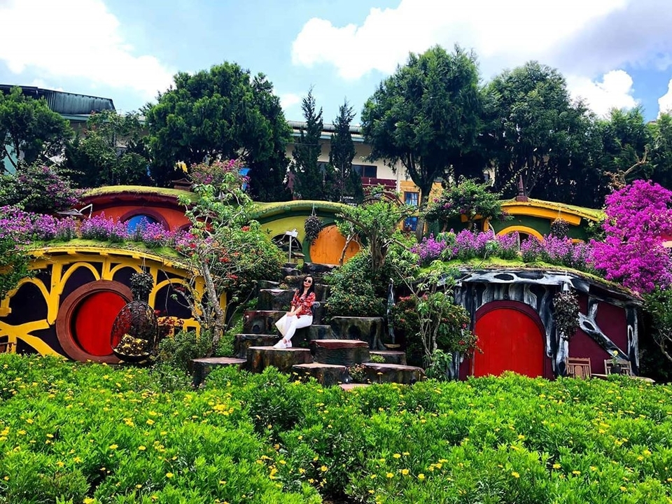 Parc coloré sur le thème de Hobbiton avec des fleurs et des portes.