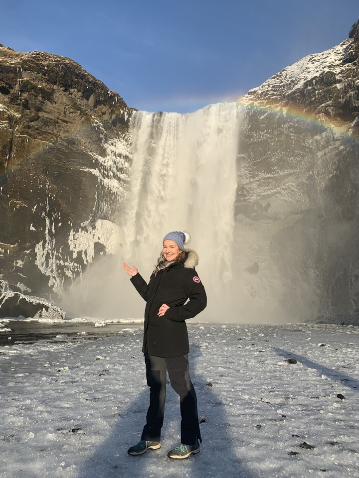 Femme posant devant une grande cascade.