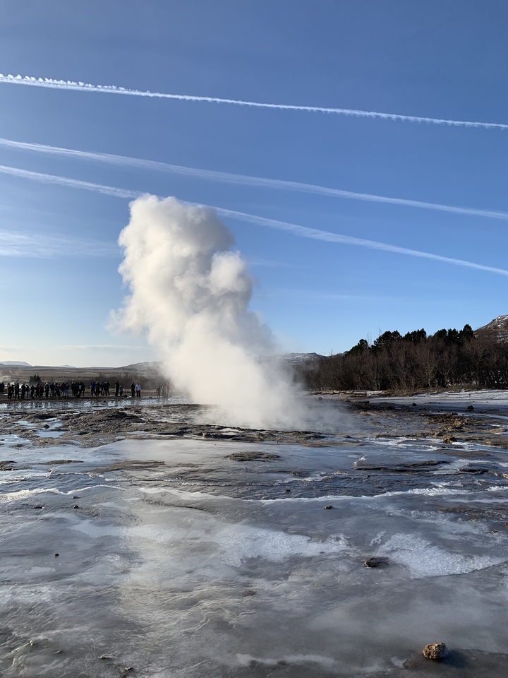Geyser en éruption avec une foule de touristes qui regardent.
