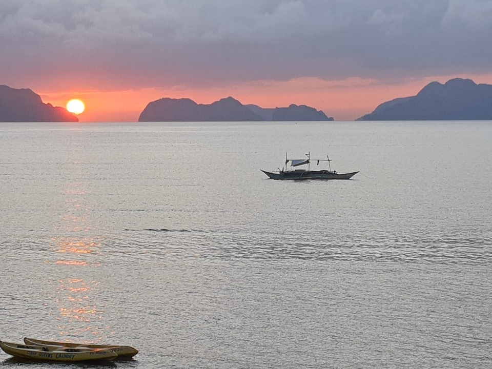 Coucher de soleil sur une mer calme avec un bateau traditionnel.