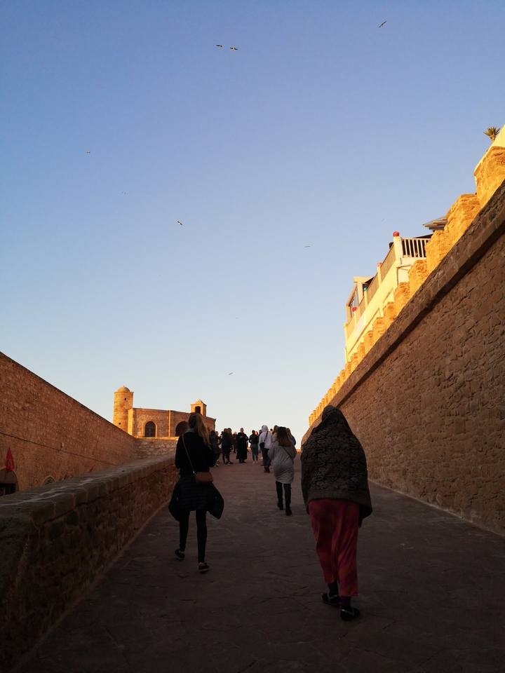 People walking on a path between ancient walls.