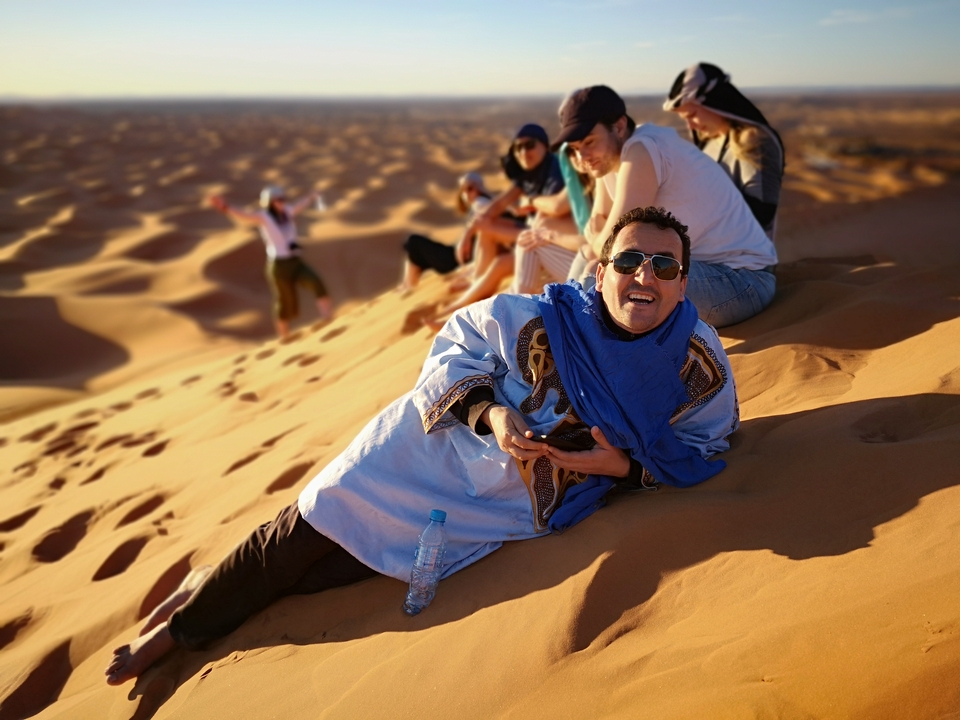 Group of people relaxing on sand dunes.