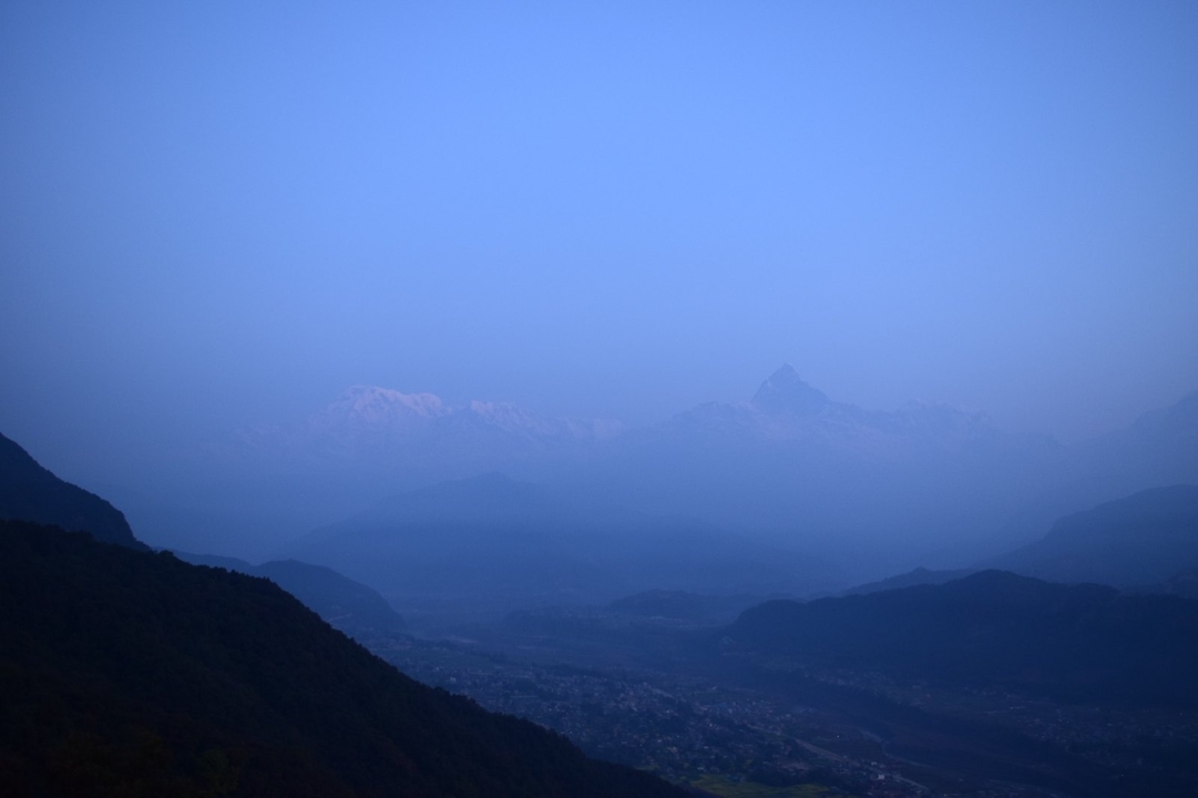 Chaîne de montagnes sous un ciel bleu profond au crépuscule.