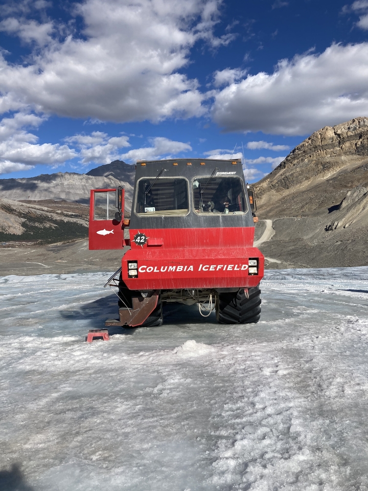 Véhicule rouge portant l'inscription « Columbia Icefield » sur un glacier avec des montagnes.