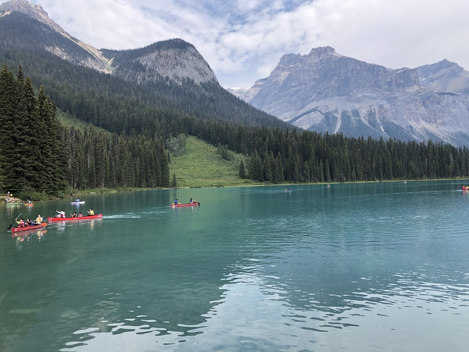 Un lac entouré de montagnes avec des gens qui font du canoë.
