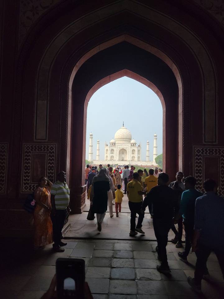 Taj Mahal eingerahmt von einem Torbogen mit Besuchern.