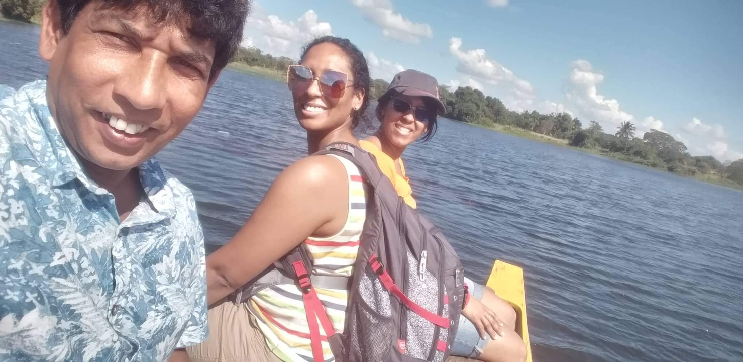 Trois personnes souriantes sur un bateau avec un lac en arrière-plan.
