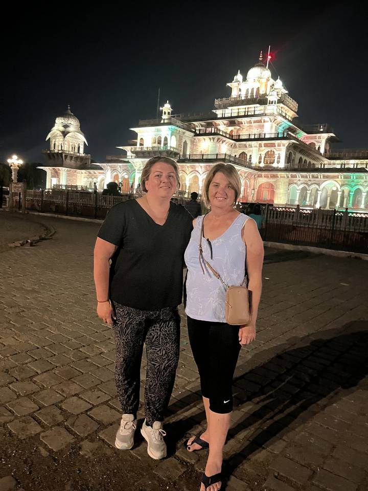 Deux personnes posant la nuit devant un palais illuminé.