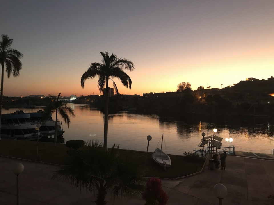 Une vue de coucher de soleil sur une rivière avec des palmiers et des bateaux.